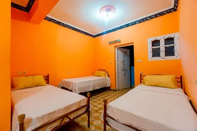 two beds in a room with orange walls at hotel dar aicha in Tinerhir
