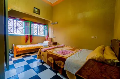 a bedroom with two beds and a tiled floor at hotel dar aicha in Tinerhir