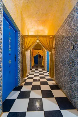 a hallway with a checkered floor and blue doors at hotel dar aicha in Tinerhir