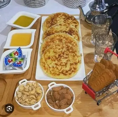 a table with two pizzas and other food on it at apartment for guests in Demnat