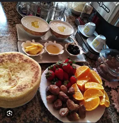 a table with a plate of food with fruit and bread at apartment for guests in Demnat