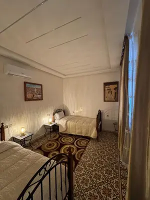 a hotel room with two beds and two tables at Appartement Dar LALA 1 in Fès