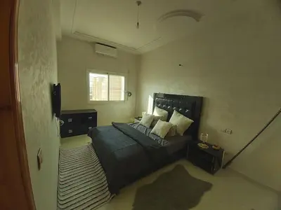a bedroom with a large bed and a rug at Location Appartement pour Familles in Fès