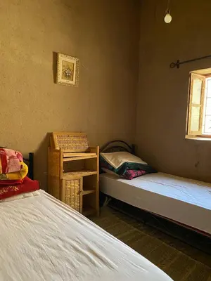 a room with two beds and a chair and a window at Dar tata in Hassilabied