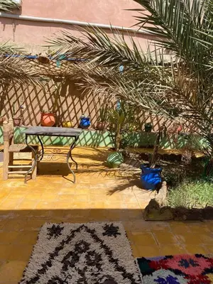 a patio with a bench and a rug and palm trees at Dar tata in Hassilabied