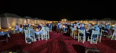 a group of people sitting at tables in a tent at Touaregs Camp Erg Lihoudi in Mhamid