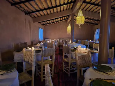 a dining room with tables and chairs and a chandelier at Touaregs Camp Erg Lihoudi in Mhamid