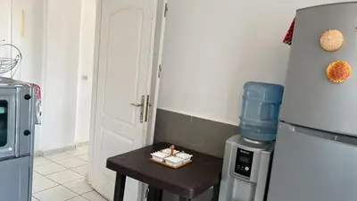 a small table in a kitchen with a refrigerator at واد فاس طريق مكناس تجزئة البركه قرب طريق الجامعه المتوسطه لاغوميد in Fès