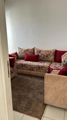 a couch with red pillows in a living room at واد فاس طريق مكناس تجزئة البركه قرب طريق الجامعه المتوسطه لاغوميد in Fès