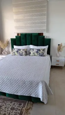 a bedroom with a white bed with green headboard and pillows at Coin des bons moments in Marrakech