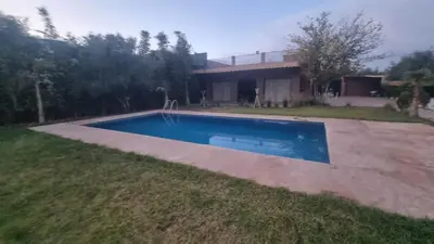 a villa with a swimming pool in front of a house at Coin des bons moments in Marrakech