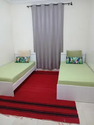 two beds in a room with a red rug at Coin des bons moments in Marrakech