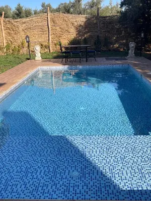a large blue swimming pool with a picnic table next to it at Sandy farm in Ouled el guerne