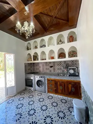 a kitchen with a washing machine and a chandelier at Sandy farm in Ouled el guerne