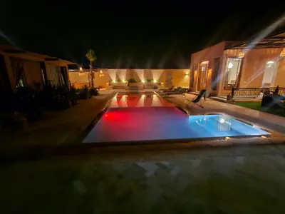 a pool with red lights in a yard at night at bled ghazal in Marrakech