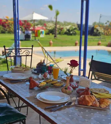 a table with breakfast food on it next to a pool at bled ghazal in Marrakech