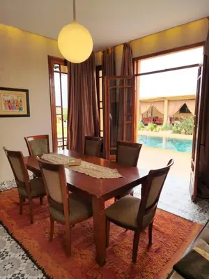 a dining room with a wooden table and chairs at bled ghazal in Marrakech