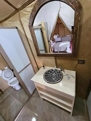 a bathroom with a sink and a mirror in a tent at Layali Luxury Desert Camp in Merzouga