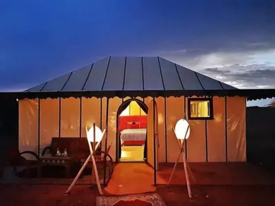 a large tent with a bed in it at night at Layali Luxury Desert Camp in Merzouga