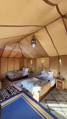 a tent bedroom with two beds and a pool at Layali Luxury Desert Camp in Merzouga