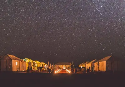 a group of huts under a starry sky at night at Layali Luxury Desert Camp in Merzouga