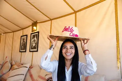 a woman is balancing a hat on her head at Luxury beldi camp in Merzouga