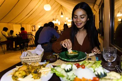 a woman sitting at a table with a plate of food at Luxury beldi camp in Merzouga