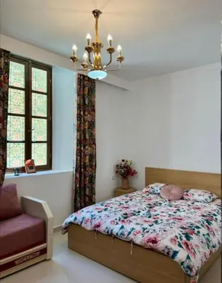 a bedroom with a bed and a chair and a chandelier at Dar House Fez in Fès