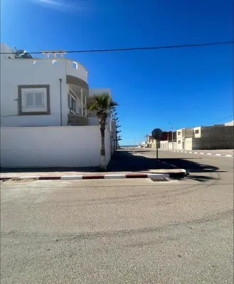 a palm tree in front of a white building at Casa de playa in Oulad Akkou