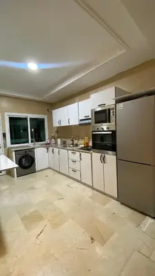 a large kitchen with white cabinets and appliances at Prestige Immo in Fès