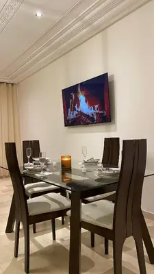 a dining room with a black table and chairs at Prestige Immo in Fès