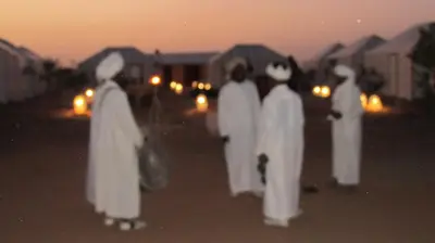 a group of nuns walking down a street at night at SANDSTAR LUXURIOUS CAMP air-conditioned in Merzouga
