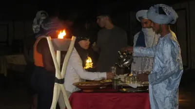 a group of people standing around a table with a candle at SANDSTAR LUXURIOUS CAMP air-conditioned in Merzouga
