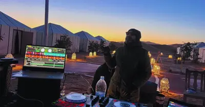 a man standing in front of a table with a laptop at SANDSTAR LUXURIOUS CAMP air-conditioned in Merzouga