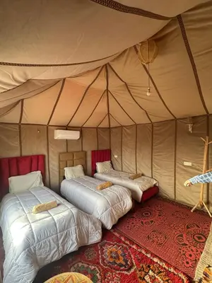 a bedroom with two beds in a tent at SANDSTAR LUXURIOUS CAMP air-conditioned in Merzouga