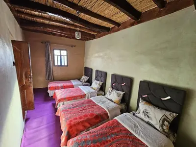 a group of four beds in a room at Gite Soleil Private House in Tacheddirt