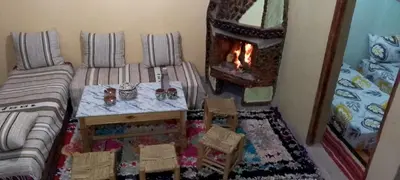 a living room with a table and a fireplace at Gite Soleil Private House in Tacheddirt
