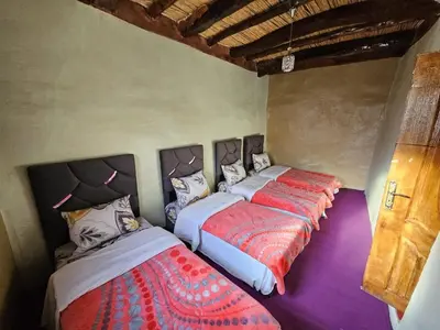 a room with three beds in it with purple floors at Gite Soleil Private House in Tacheddirt