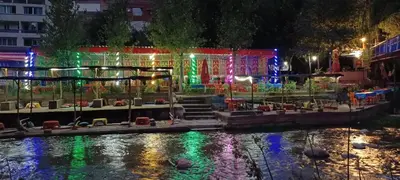 a garden lit up at night next to a river at siti fadma ourika Marrakech in Aghbalou