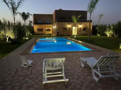 a swimming pool with two chairs and a house at Tasnim VILLA in Marrakech