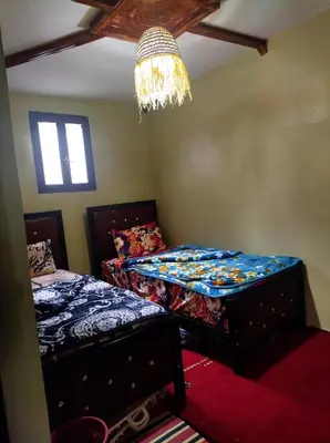 a bedroom with two twin beds and a chandelier at Gîte Assonfo Tachdirt in Tacheddirt