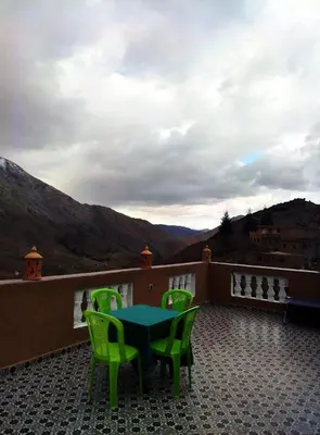 a patio with a table and chairs on a balcony at Gîte Assonfo Tachdirt in Tacheddirt