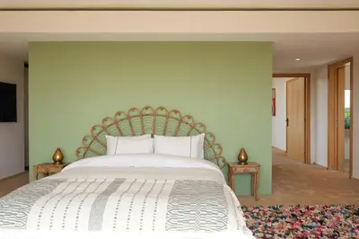 a bedroom with a large white bed with a green wall at Villa Shelter in El Bougaria