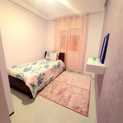 a small bedroom with a bed and a rug at Appartement confortable in Fès