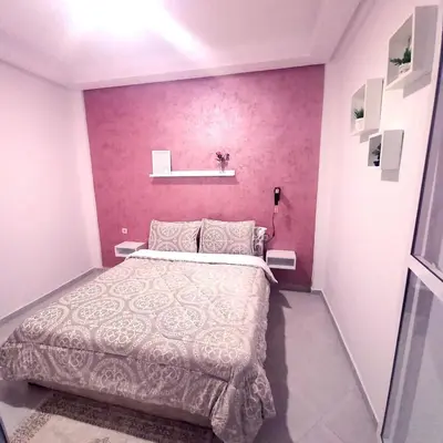 a bedroom with a large bed and a pink wall at Appartement confortable in Fès