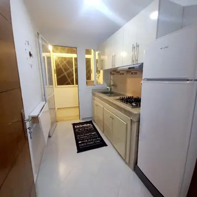 a kitchen with a white refrigerator and a white tile floor at Appartement confortable in Fès