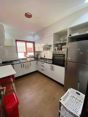 a large kitchen with white cabinets and a refrigerator at Appartement luxueuse au centre ville de Fès in Fès