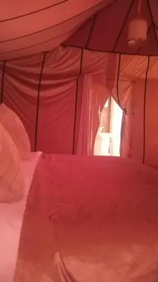 a bed with a red comforter in a tent at Merzouga morocco in Tisserdmine