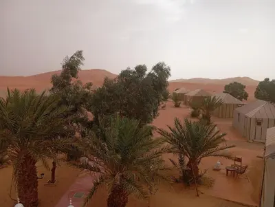 an aerial view of a desert with tents and palm trees at Merzouga morocco in Tisserdmine