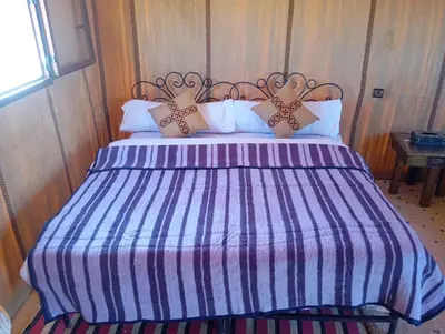 a large bed with a blue and white striped comforter at Merzouga morocco in Tisserdmine